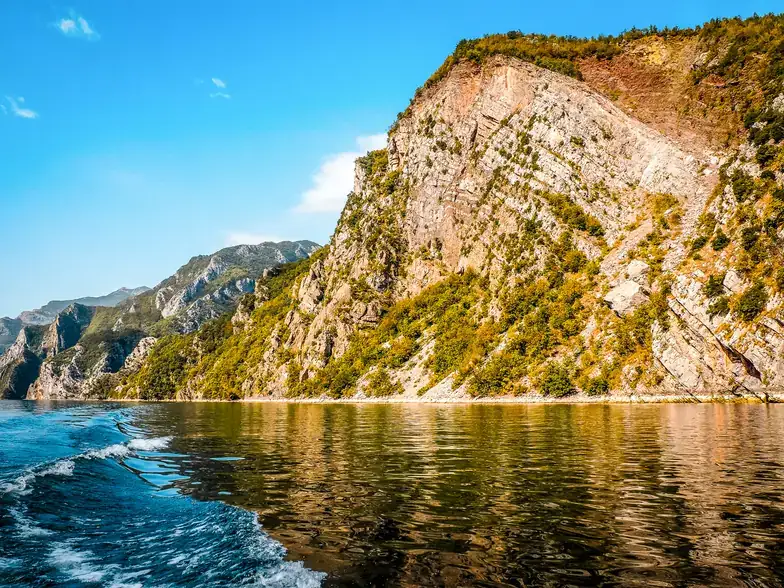 A small boat dwarfed by the limestone walls of the Komani gorge